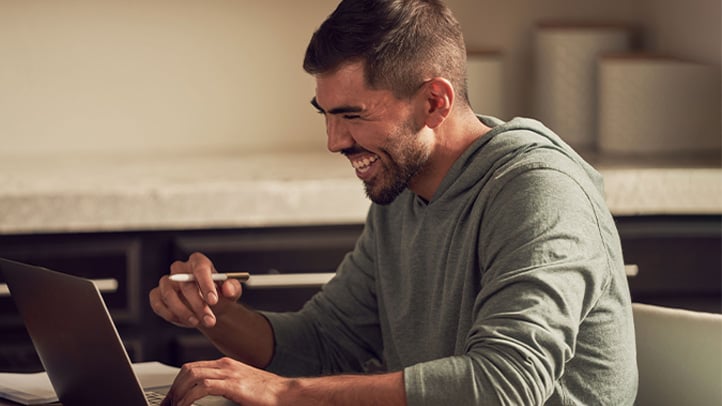 Man looking at laptop taking notes