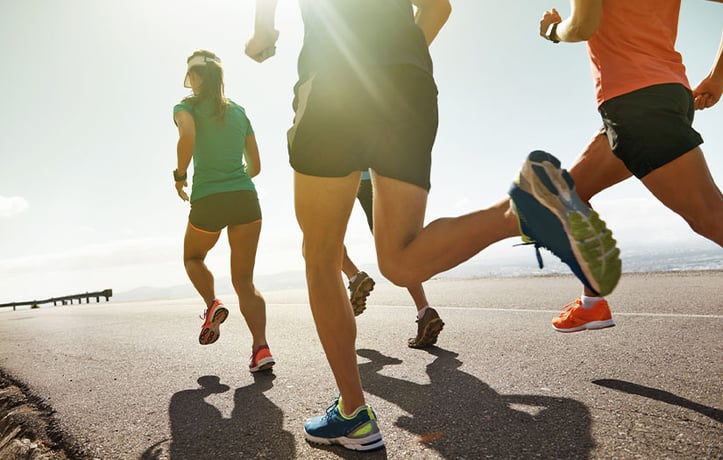 4 athletes running outside along water