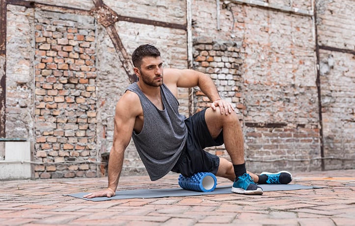 man using foam roller on outside hip area