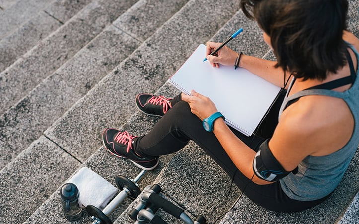 person setting smart fitness goals for herself with a notepad
