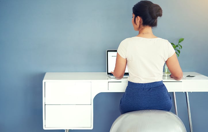 woman sitting on a medicine ball at her desk