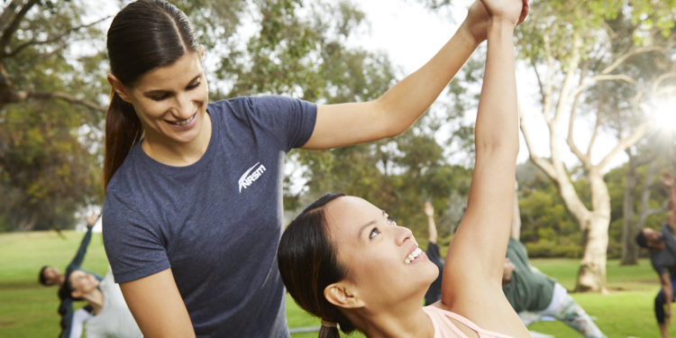 Female NASM trainer assisting client in side yoga pose