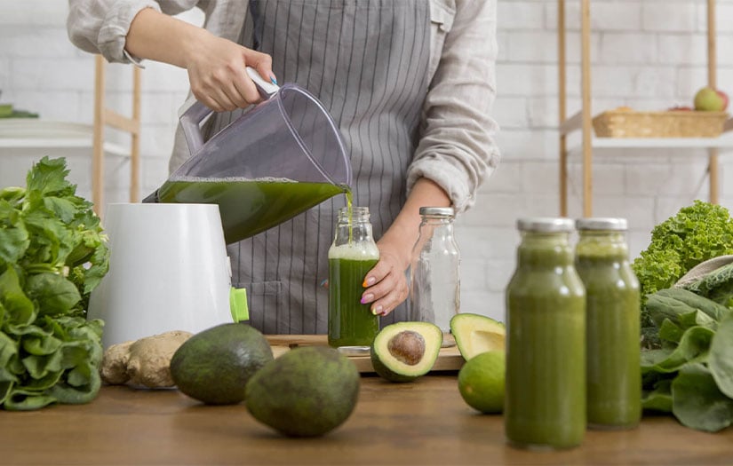 Person making green juice in kitchen