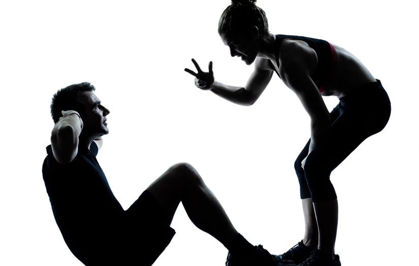 Trainer helping client with sit ups