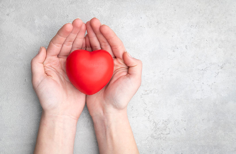 hands holding a heart shaped stress ball