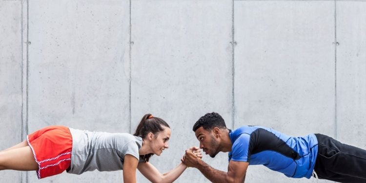 female and male doing a plank and cross holding hands