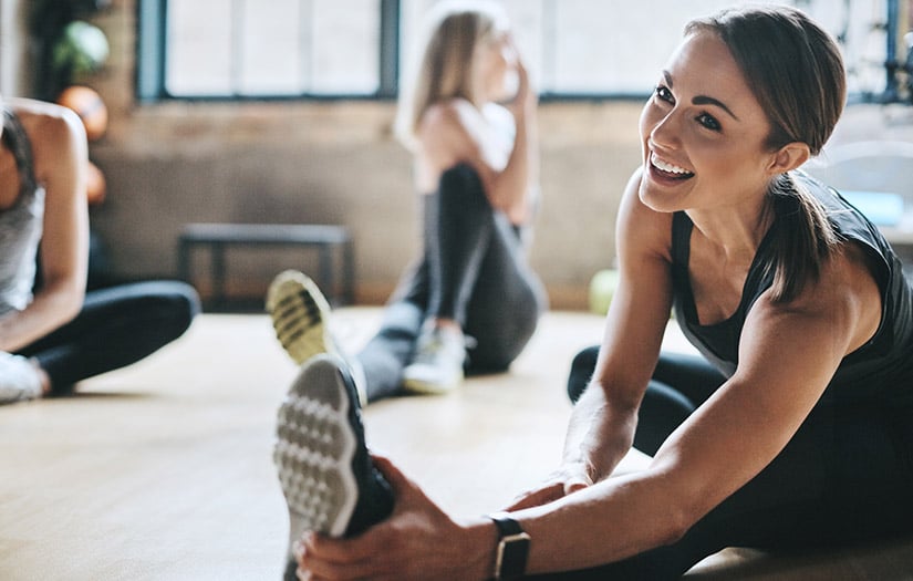 a smiling woman doing dynamic stretches