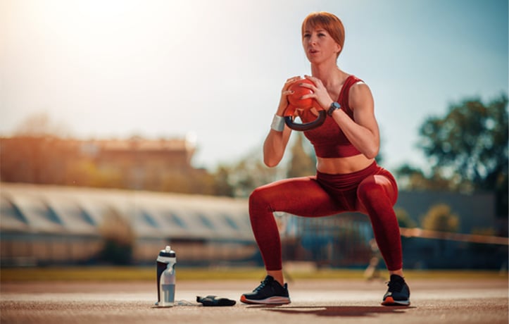 A woman doing a goblet squat in a park