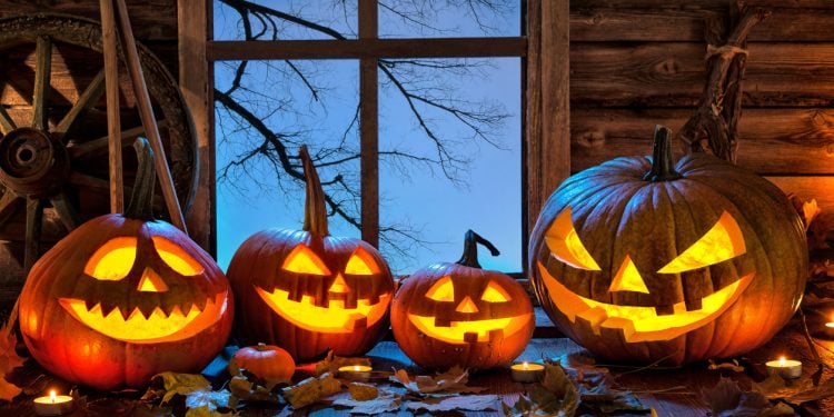 Carved halloween pumpkins sitting next to window seal