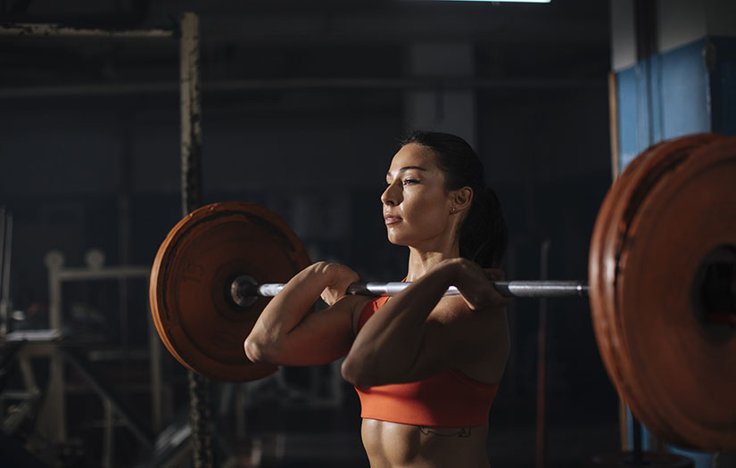 woman doing a front squat with a barbell and plates