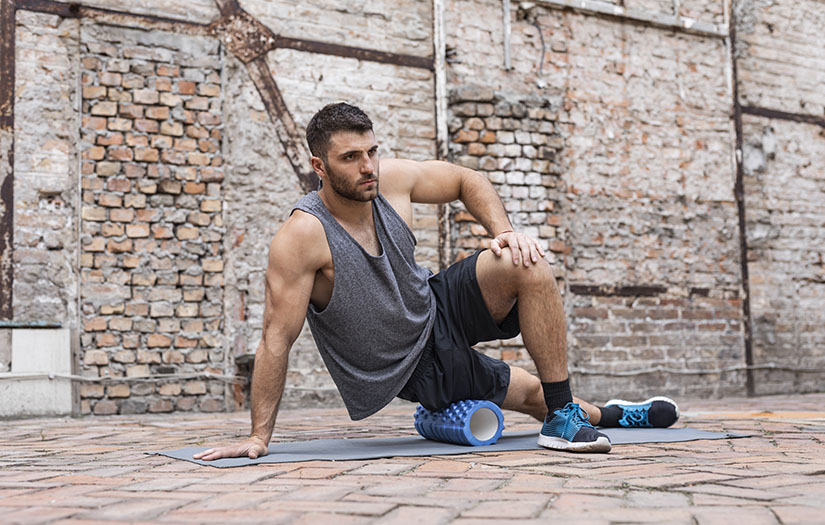 man using foam roller on outside hip area