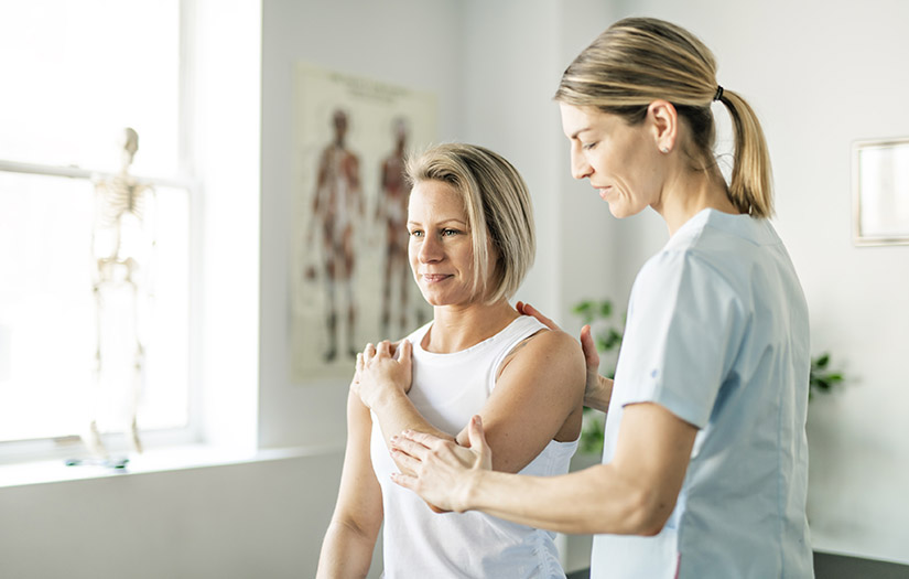physiotherapist helping a woman's range of motion in shoulder