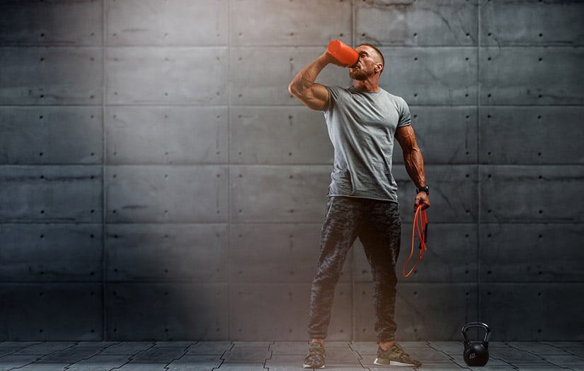 male drinking out of shaker bottle with jump rope in hand