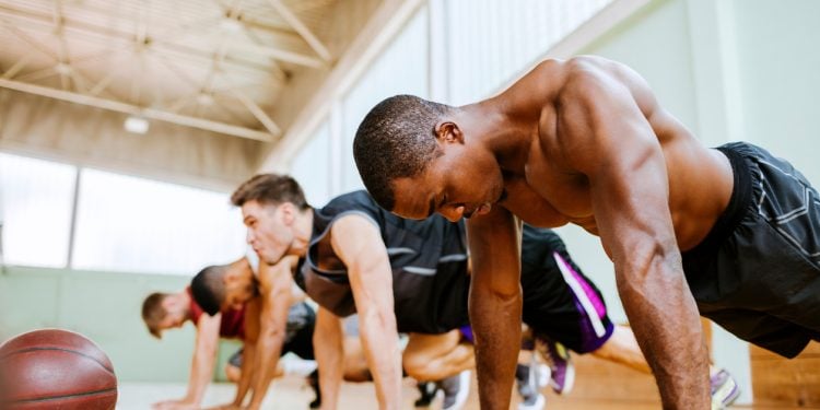 Athletes doing plans inside basketball gym