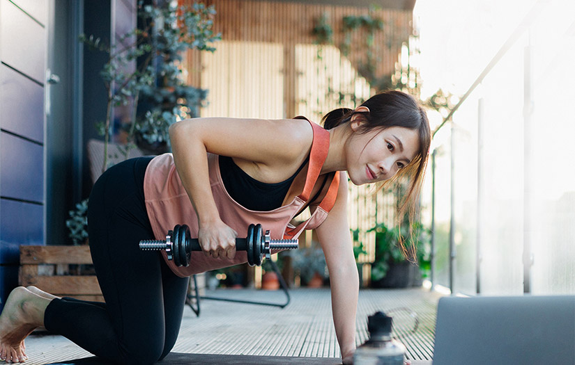 trainer doing bent-over rows in front of laptop